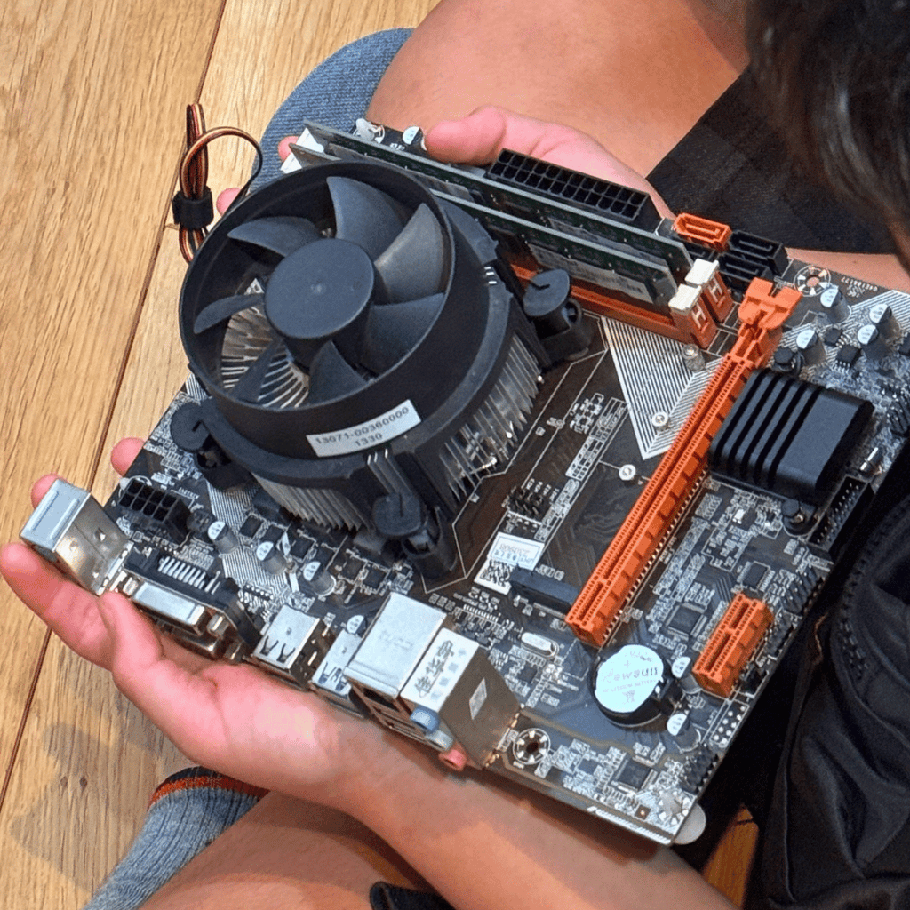 マザーボードを膝に乗せて見つめる参加者の写真